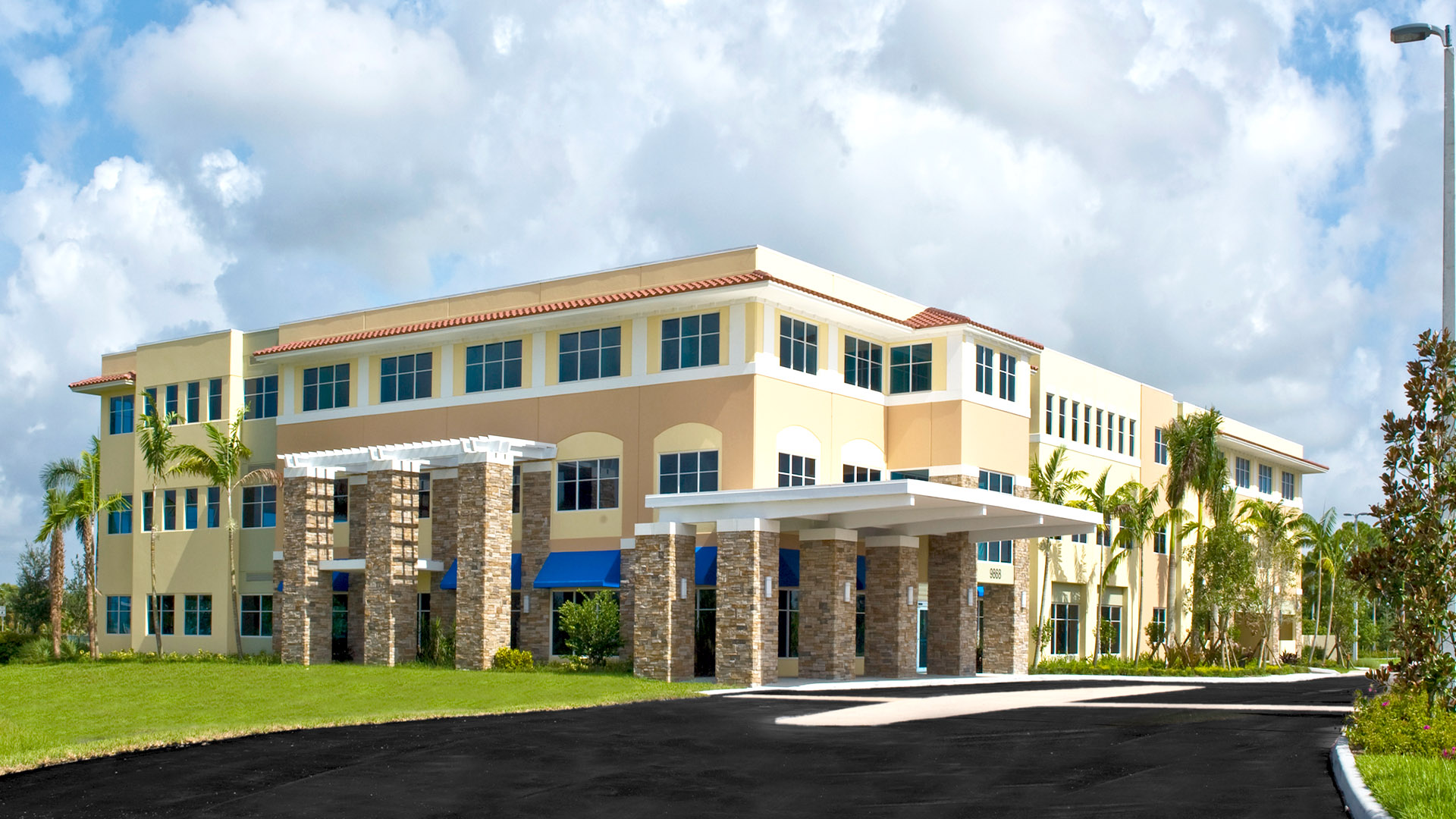 Bethesda Hospital West exterior view featuring modern architecture, palm trees, and landscaped surroundings, emphasizing its role as a community healthcare facility in Palm Beach County.