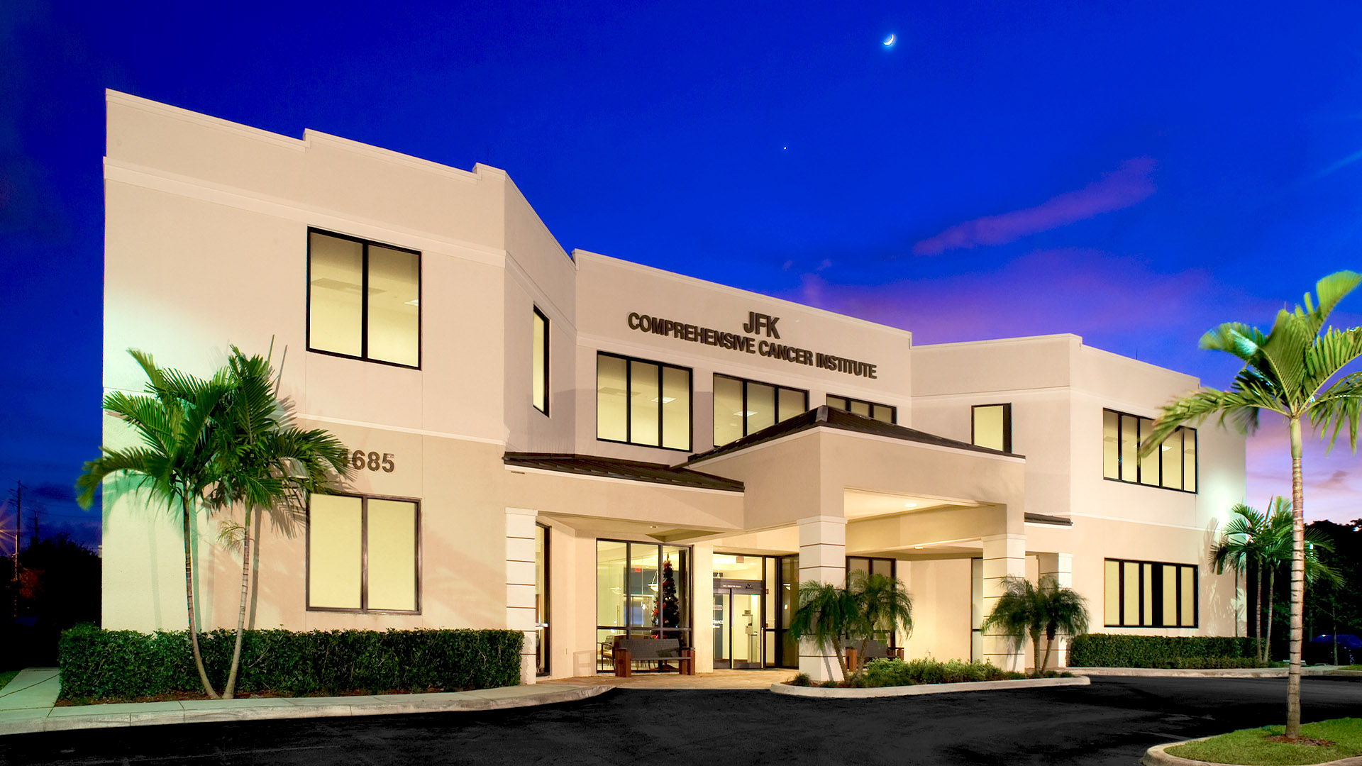 JFK Comprehensive Cancer Institute building exterior at dusk, showcasing modern architecture and landscaping in Deerfield Beach, FL, emphasizing healthcare construction.