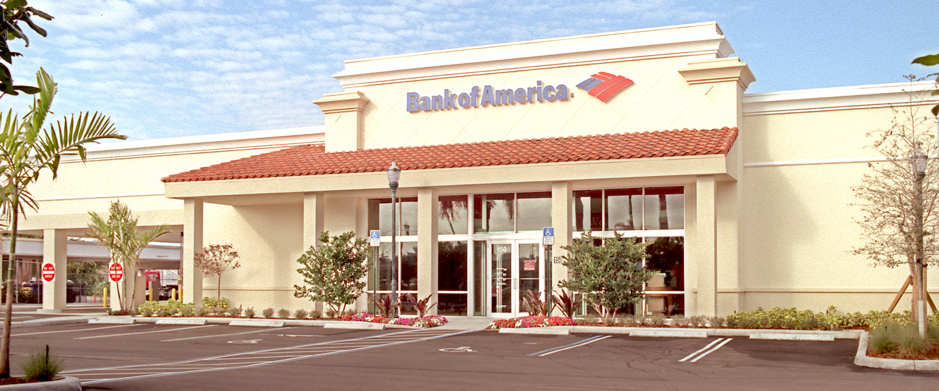 Bank of America branch exterior in West Palm Beach, FL, showcasing modern architecture, landscaped entrance, and parking area, reflecting financial stability and customer accessibility.