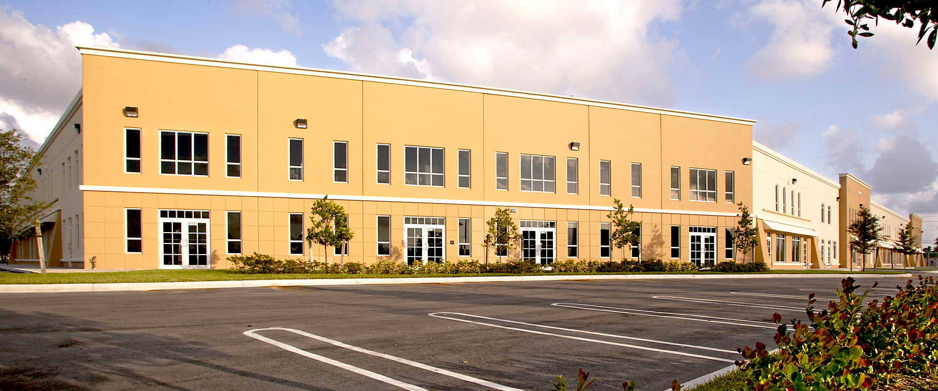 Industrial facility exterior showcasing modern architecture, large windows, and landscaped surroundings, emphasizing productivity and innovation in industrial construction by Leighton McGinn.