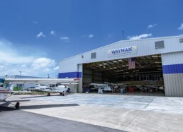 A hangar with airplanes parked in it and people standing around.