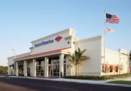 A bank of america branch with an american flag flying in the background.