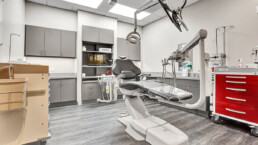 A dentist 's office with an empty chair and some equipment.