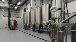 A room filled with many stainless steel tanks.