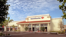 A bank of america branch in the middle of a parking lot.