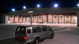 A van parked in front of an airport hangar.