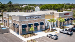 A mattress firm store with cars parked in front of it.