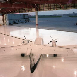 A large white airplane parked in an airport hangar.
