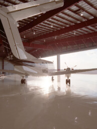 A large hangar with two airplanes parked in it.